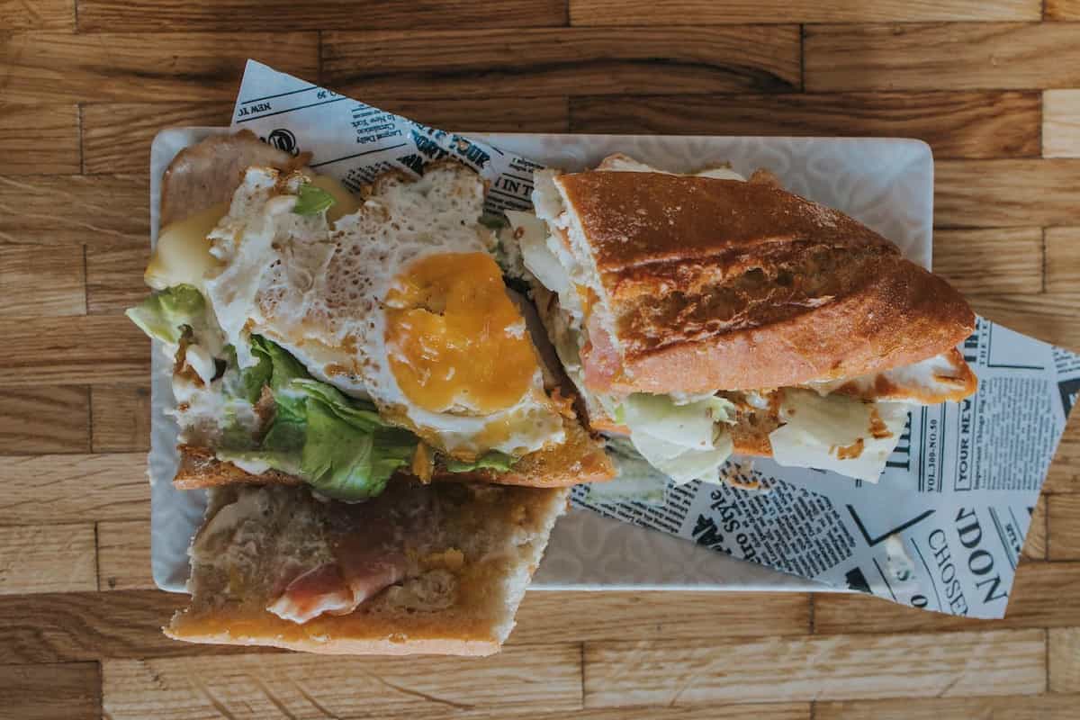 Bocadillo tipo chivito con huevo, carne y vegetales frescos
