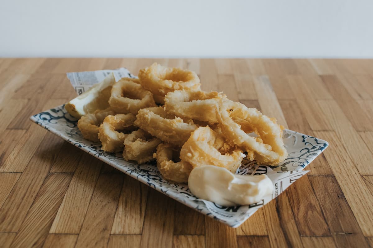 Ración de crujientes calamares a la romana con limón y alioli